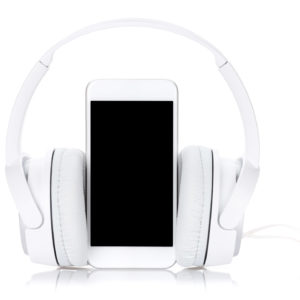 Ein weißes Smartphone steht mittig von On-Ear Kopfhörern